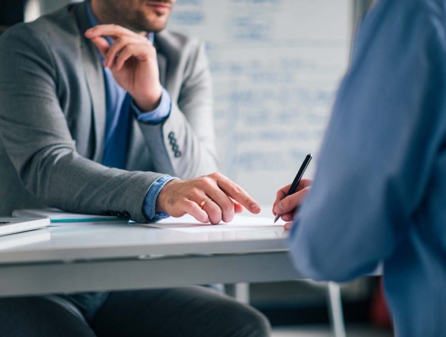 low-angle-image-two-men-formal-wear-sitting-desk-signing-agreement-min-scaled